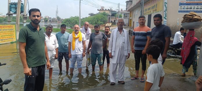 गांव में भरे हुए पानी को दिखाते हुए ग्रामीण